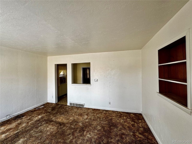 empty room with built in features, dark colored carpet, visible vents, a textured ceiling, and baseboards