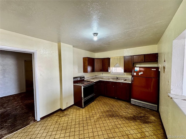 kitchen featuring freestanding refrigerator, light countertops, range with electric stovetop, and a sink