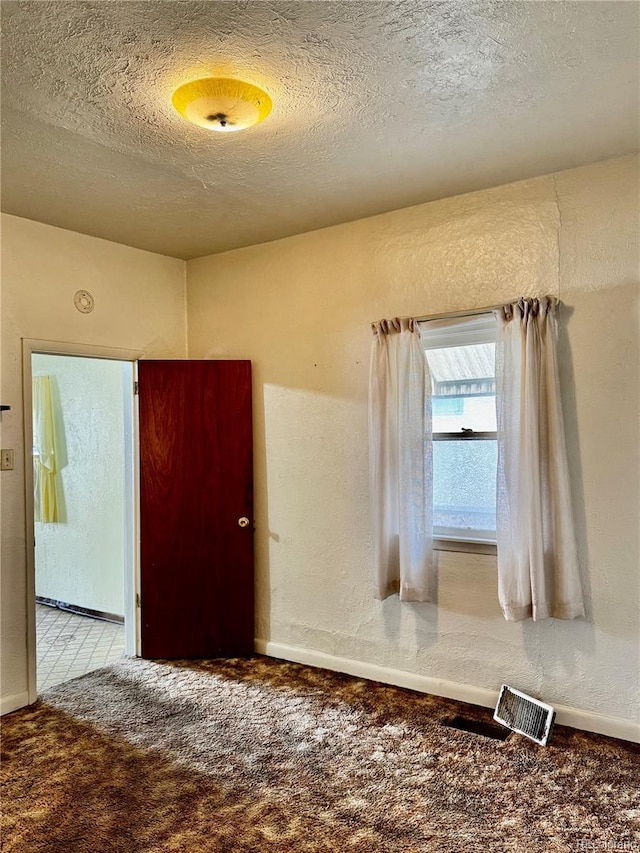 carpeted spare room with a textured wall and a textured ceiling