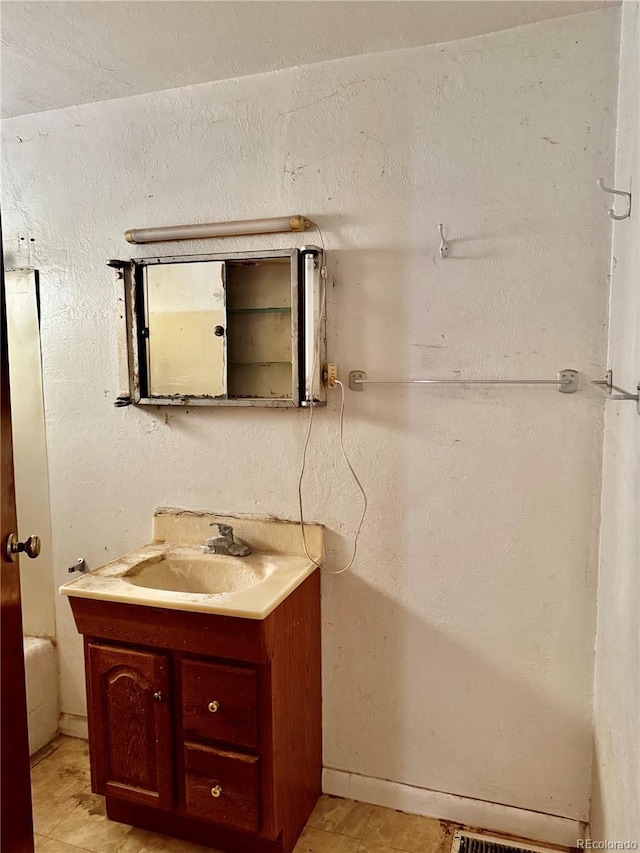 bathroom featuring a textured wall and vanity