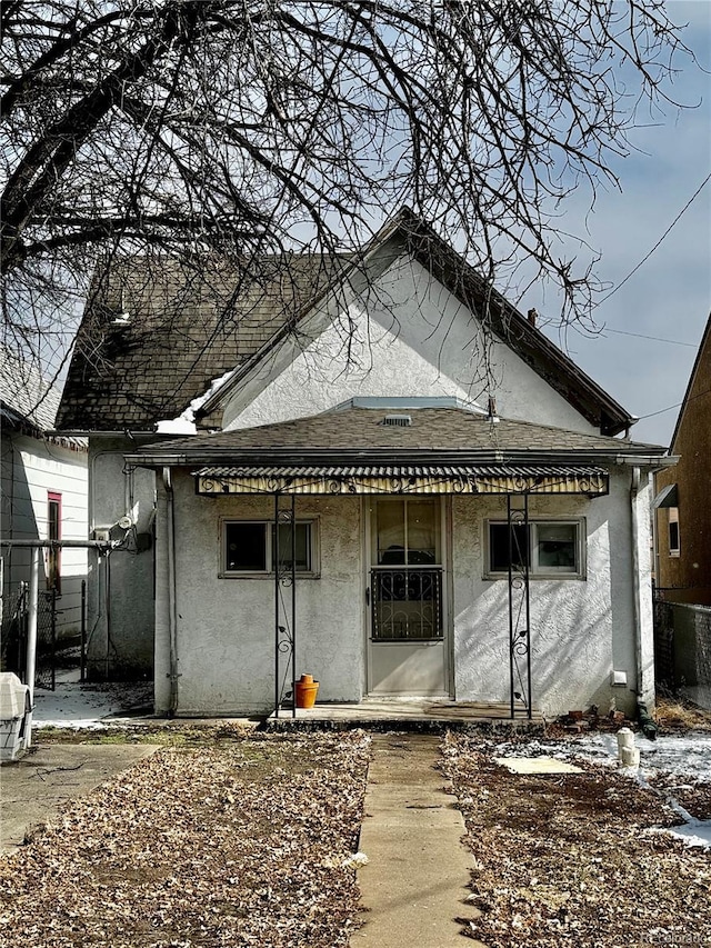 rear view of property featuring roof with shingles and stucco siding