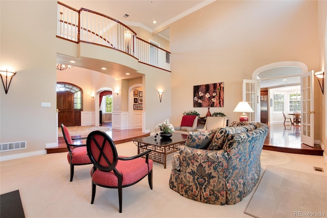 carpeted living room featuring a high ceiling, french doors, and crown molding