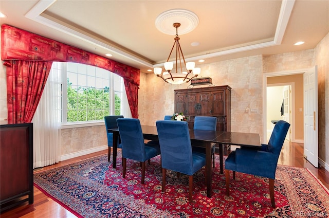 dining room with wood-type flooring, a chandelier, and a tray ceiling