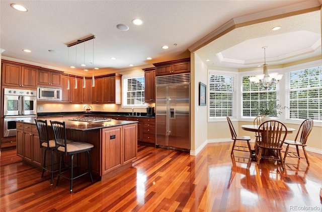 kitchen with a center island, pendant lighting, built in appliances, and plenty of natural light