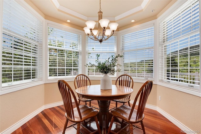 dining room featuring hardwood / wood-style floors, a chandelier, ornamental molding, and a tray ceiling