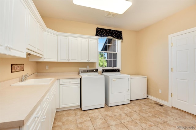 laundry area featuring cabinets, light tile patterned flooring, washer and dryer, and sink