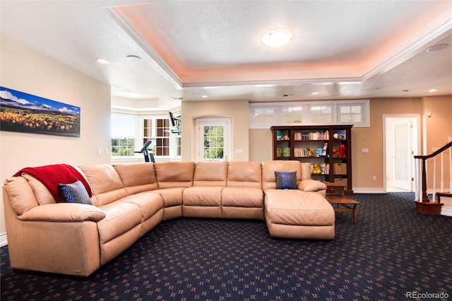 living room with a textured ceiling, carpet, and a tray ceiling