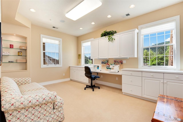 carpeted office with built in desk and plenty of natural light