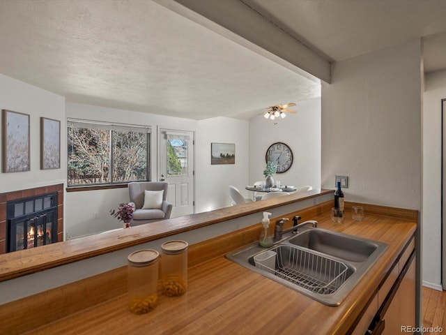 kitchen featuring a fireplace, ceiling fan, and a sink