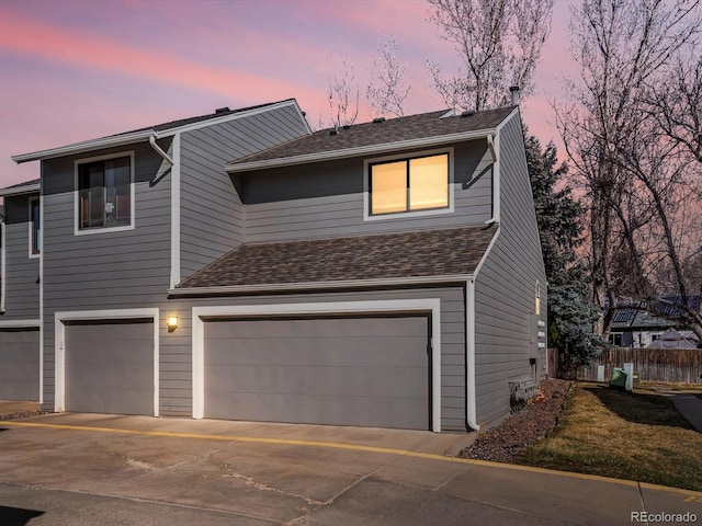 view of front of property featuring roof with shingles, driveway, a garage, and fence
