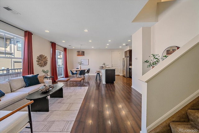 living area featuring recessed lighting, dark wood-style flooring, visible vents, baseboards, and stairway