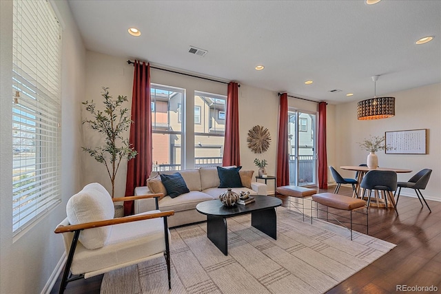 living area with recessed lighting, visible vents, baseboards, and wood finished floors