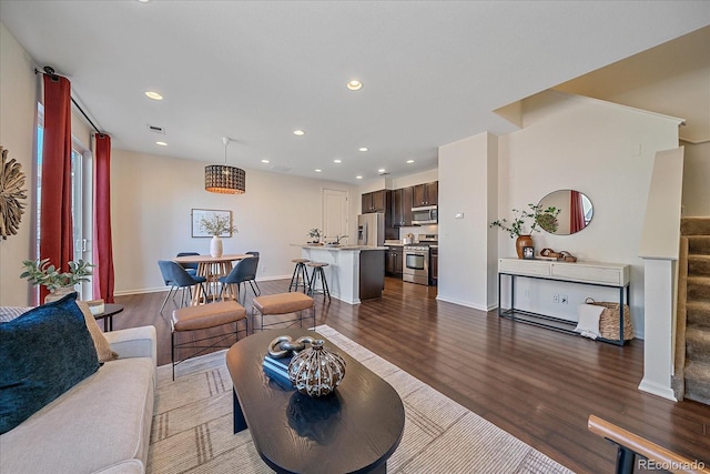 living area featuring baseboards, visible vents, wood finished floors, stairs, and recessed lighting