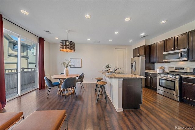 kitchen featuring dark wood-style floors, stainless steel appliances, a sink, and visible vents