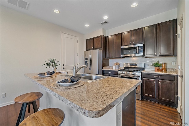 kitchen featuring a breakfast bar area, tasteful backsplash, visible vents, appliances with stainless steel finishes, and a sink