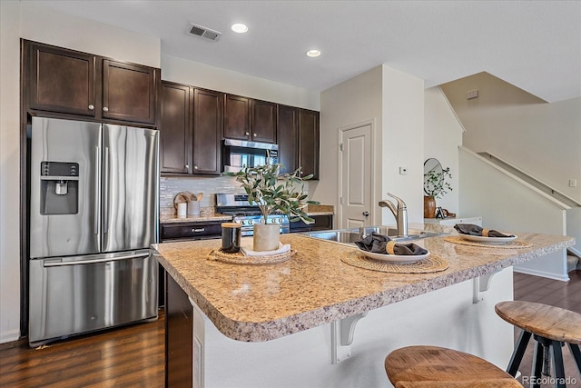 kitchen featuring stainless steel appliances, a breakfast bar area, a sink, and visible vents