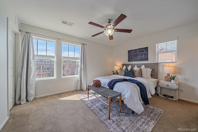 carpeted bedroom featuring a ceiling fan, visible vents, and baseboards