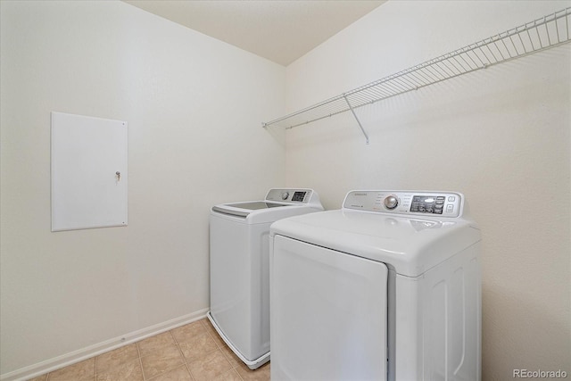 laundry room featuring light tile patterned floors, laundry area, washing machine and dryer, and baseboards