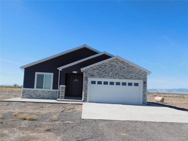 view of front of house featuring driveway, stone siding, and a garage