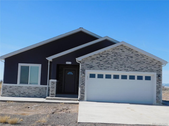 view of front of house with stone siding, driveway, and an attached garage