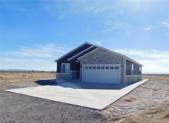 view of side of home featuring a garage, driveway, and stone siding