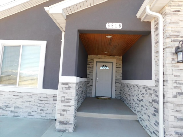 doorway to property with stone siding and stucco siding