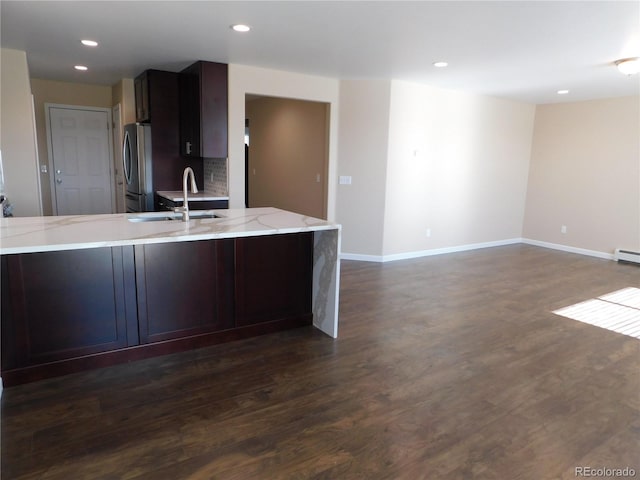 kitchen with recessed lighting, a sink, freestanding refrigerator, light stone countertops, and dark wood finished floors