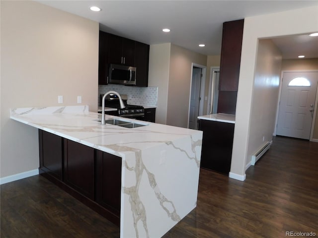 kitchen with decorative backsplash, dark wood-style floors, appliances with stainless steel finishes, a peninsula, and baseboard heating