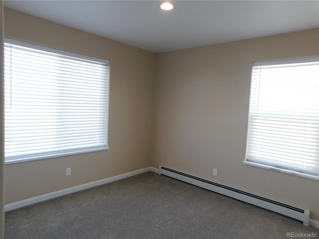 spare room featuring a healthy amount of sunlight, a baseboard heating unit, and carpet flooring