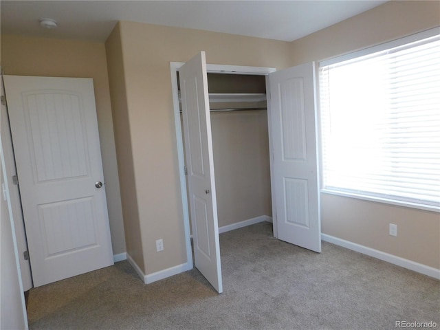 unfurnished bedroom featuring carpet, a closet, and baseboards