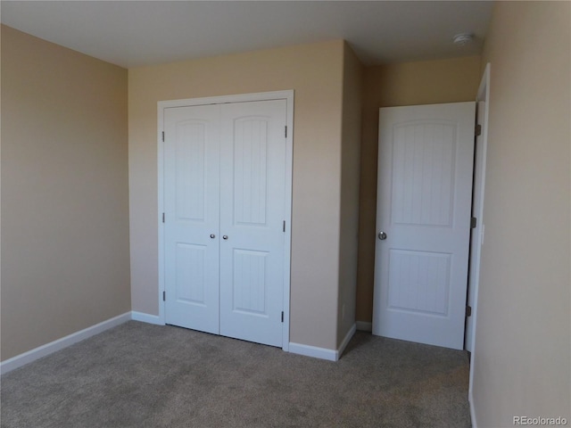 unfurnished bedroom with a closet, carpet flooring, and baseboards