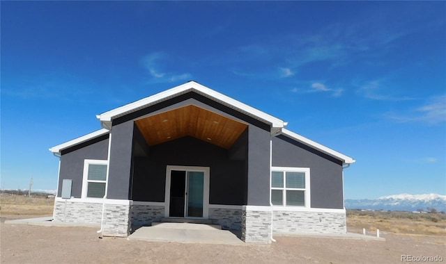 back of property featuring stone siding and stucco siding