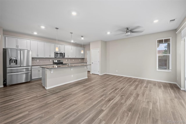 13870 Ash Cir, Brighton, CO 80602 - kitchen with stainless steel appliances, a ceiling fan, recessed lighting, light wood-style floors, and a kitchen breakfast bar