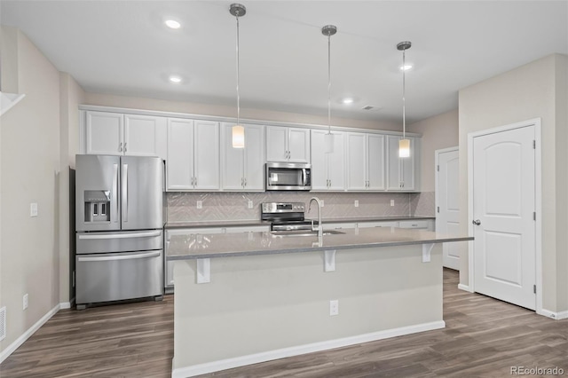 13870 Ash Cir, Brighton, CO 80602 - kitchen featuring stainless steel appliances, dark wood-style floors, decorative backsplash, a kitchen island with sink, and recessed lighting