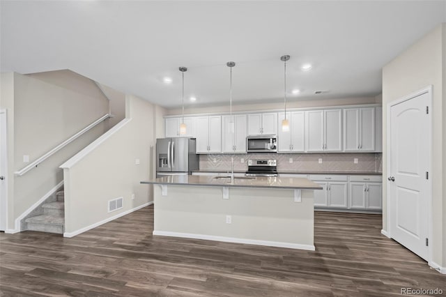 13870 Ash Cir, Brighton, CO 80602 - kitchen with appliances with stainless steel finishes, dark wood-type flooring, a kitchen island with sink, backsplash, and recessed lighting