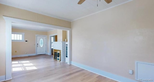 unfurnished living room featuring a fireplace, a ceiling fan, baseboards, light wood-style floors, and ornamental molding