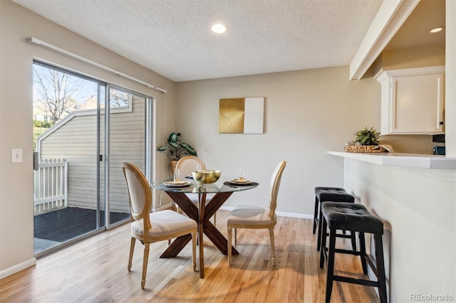 dining area with a textured ceiling and light hardwood / wood-style floors