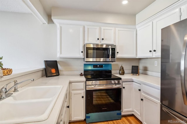 kitchen featuring white cabinetry, sink, stainless steel appliances, and light wood-type flooring