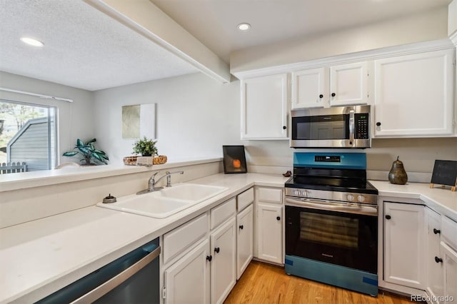 kitchen featuring white cabinets, light wood-type flooring, sink, and appliances with stainless steel finishes