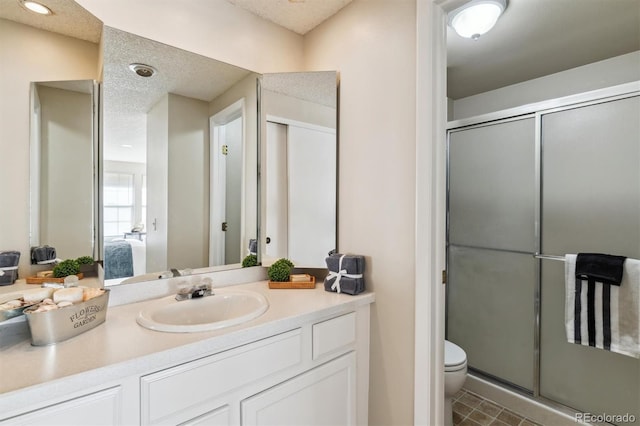 bathroom featuring vanity, a shower with shower door, a textured ceiling, and toilet