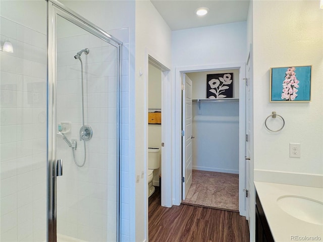 bathroom with walk in shower, wood-type flooring, toilet, and vanity