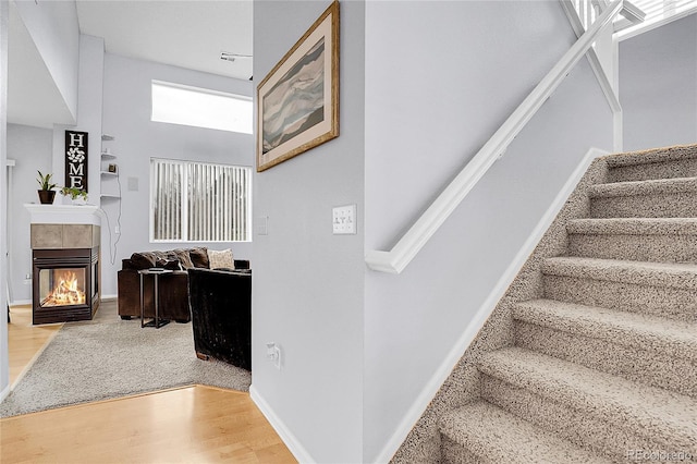 14944 E Archer Cir, Aurora, CO 80012 - staircase with wood finished floors, a multi sided fireplace, a towering ceiling, and baseboards