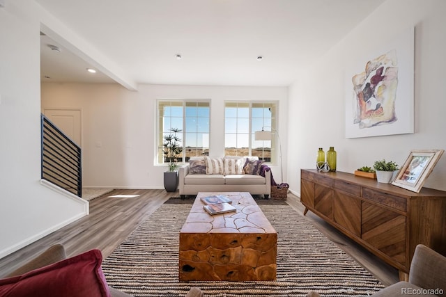 living area with beamed ceiling, wood finished floors, recessed lighting, stairway, and baseboards