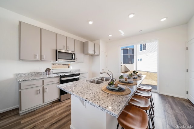 kitchen with dark wood-style flooring, gray cabinets, stainless steel appliances, and a sink