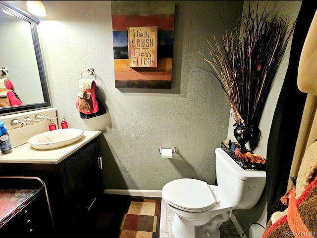bathroom featuring vanity, baseboards, and toilet
