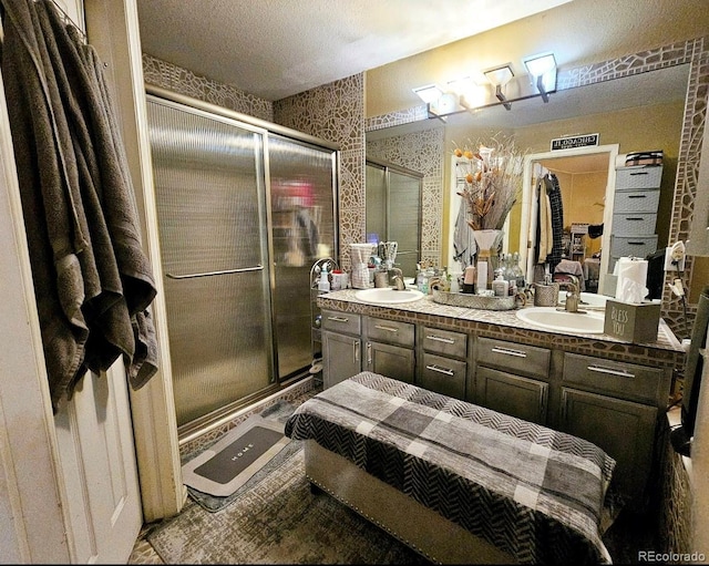 full bath featuring a stall shower, double vanity, and a sink