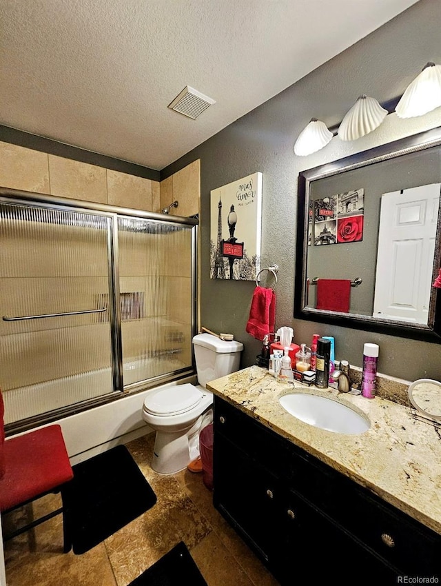 bathroom with vanity, a textured ceiling, toilet, visible vents, and bath / shower combo with glass door