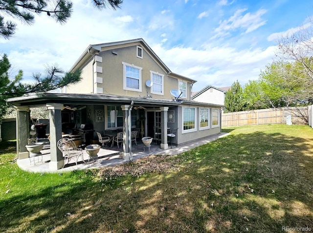 rear view of house with a patio, a yard, stucco siding, and fence