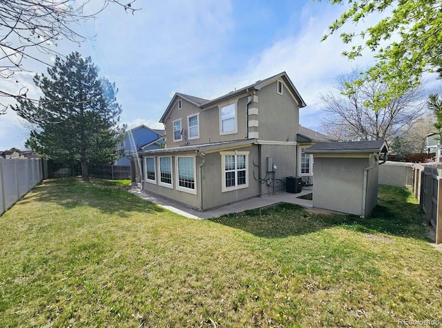 rear view of house featuring a yard, a fenced backyard, stucco siding, and central AC