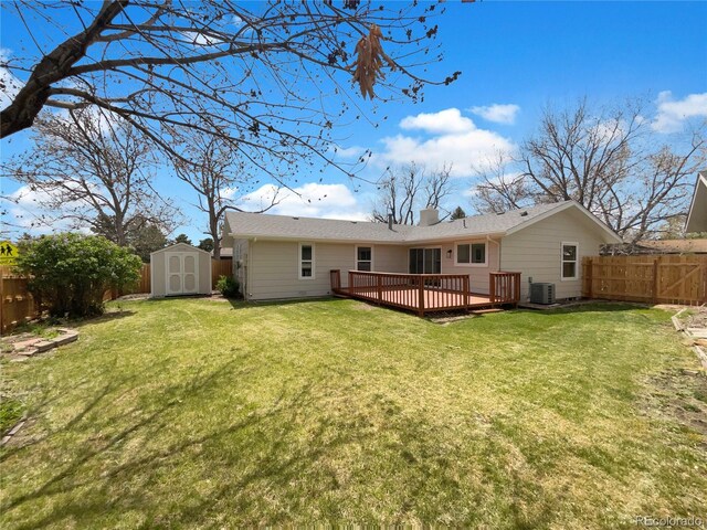 rear view of house with a storage shed, a wooden deck, a lawn, and a fenced backyard